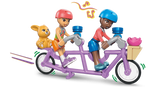 Two LEGO Friends minidolls wearing pink and blue helmets riding a purple tandem bicycle, with a brown bunny in the rear basket and pink flower in the front basket.