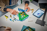 Person assembling LEGO Editions Vini Jr. Football Highlights 43027 on a table with loose LEGO bricks, a partially completed football display and tablet showing digital building instructions.