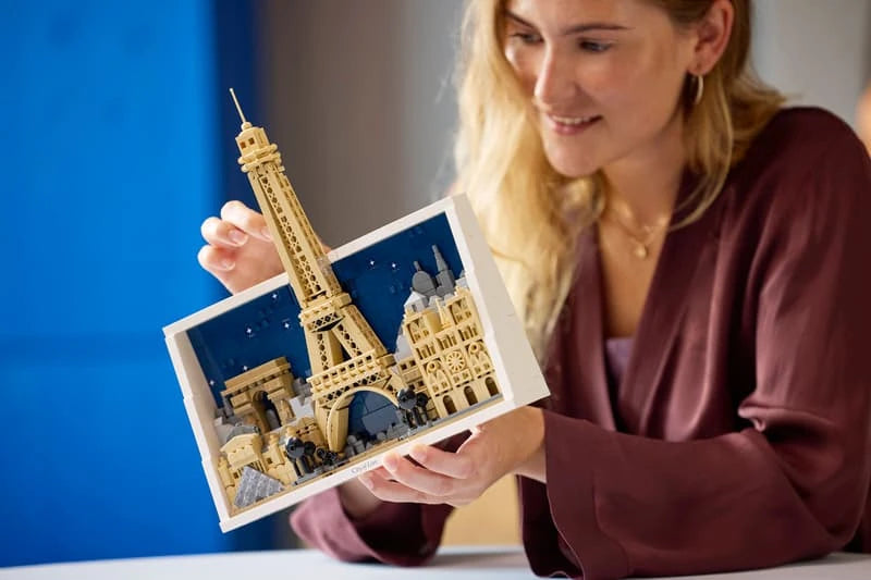 Woman holding the completed LEGO Architecture Paris City of Love model with the Eiffel Tower and framed skyline visible