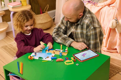 Child and adult building LEGO Beach Fun with Lilo & Stitch on a green table with a tablet nearby