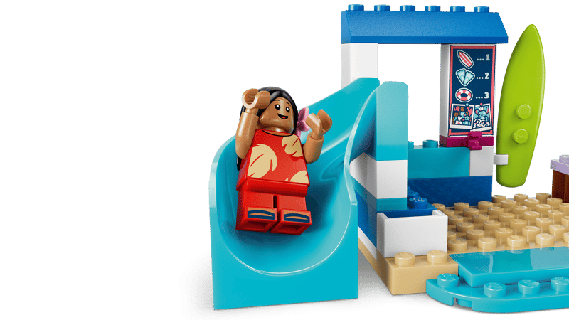 LEGO Lilo figure seated on a blue slide beside a beach sign and surfboard