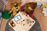 Child building LEGO Belle & the Beast's Enchanted Castle on a table with a tablet nearby