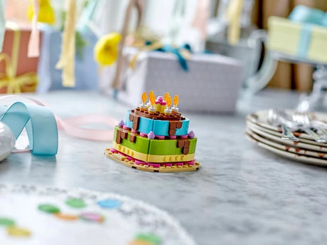 LEGO birthday cake model displayed on a table with party decorations in the background
