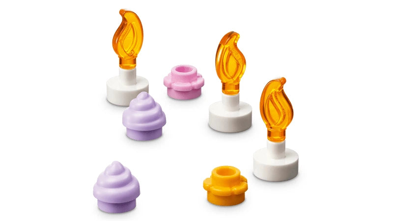 LEGO candle pieces with orange flames beside pink, yellow and purple cake decorations