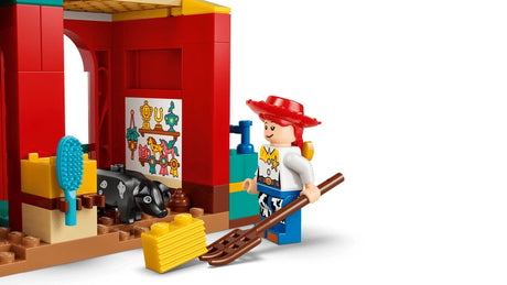 Jessie standing beside the barn interior with the black pig, brush, hay bale and pitchfork on a white background