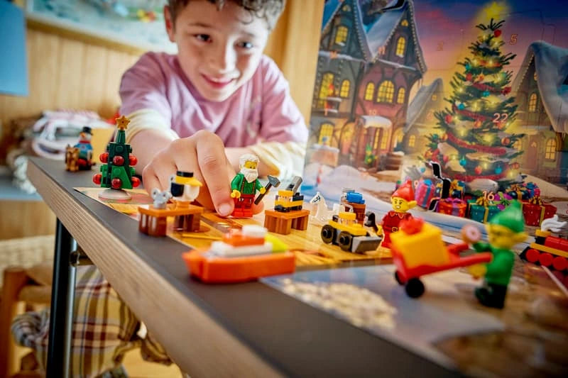 Child playing with LEGO City Advent Calendar figures, a reindeer, sleigh and festive mini builds