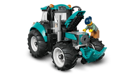 Front angled view of LEGO City Farm Tractor 60498 with hood open revealing engine detail, teal body panels, cab structure and farmer minifigure positioned beside the tractor