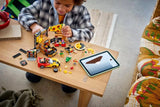 Child building a LEGO City pizza delivery set on a table with sports car, scooter, minifigures and tablet instructions