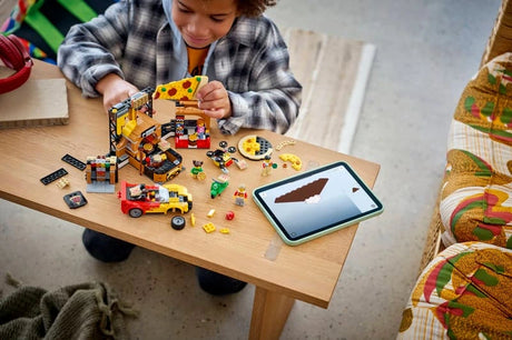 Child building a LEGO City pizza delivery set on a table with sports car, scooter, minifigures and tablet instructions
