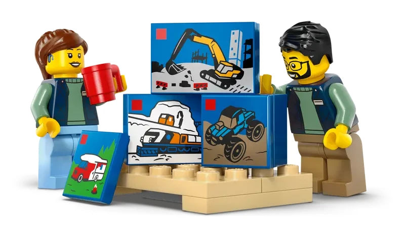Two LEGO City minifigures standing beside four miniature LEGO boxes with printed vehicle designs stacked on a tan base plate
