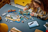 Child building a LEGO City streetcar set at a table with pieces, streetcar model, pier section and tablet instructions