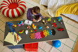 Child at a table with LEGO bricks, built models and drawing materials