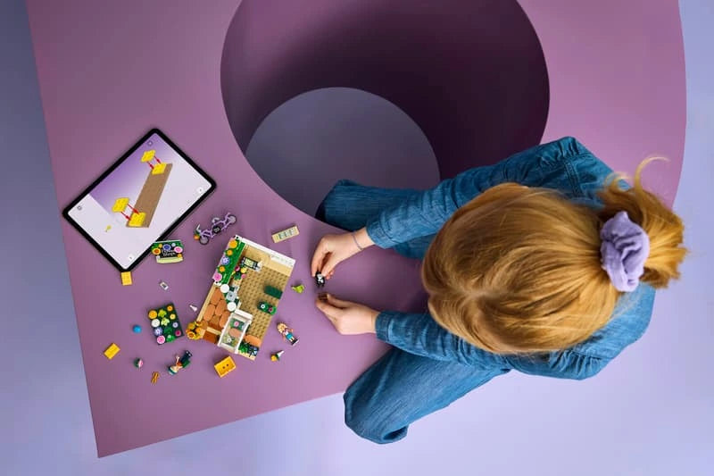 Child building LEGO Creative Flower Shop with loose pieces and instructions on a table