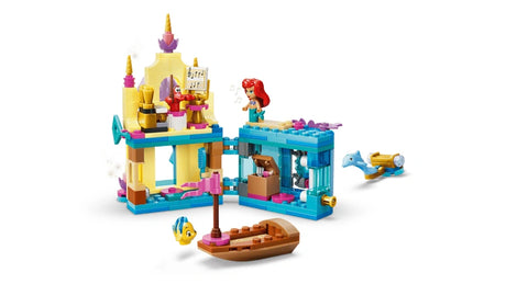 Opened Ariel mini palace showing interior rooms with hinged sections and a small boat placed in front on a white background
