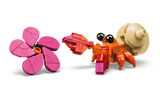 Close-up of the small orange LEGO Disney hermit crab with black eyes, beige shell and red claws beside a brick-built pink flower with five petals.