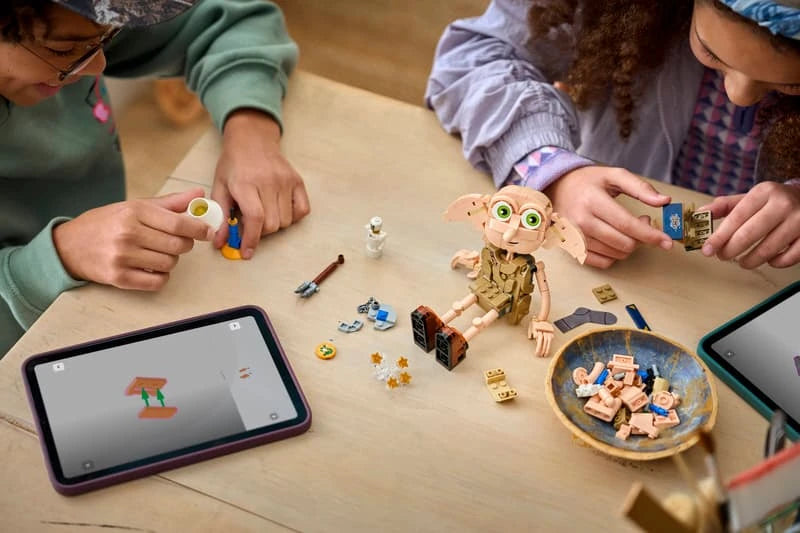 Children building a LEGO Dobby figure set at a table with pieces and tablet instructions