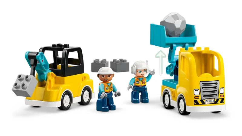 Assembled LEGO DUPLO yellow dump truck and loader with teal excavator arm, two DUPLO figures and loose grey bricks displayed together