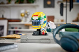 LEGO Ayrton Senna Helmet 43024 displayed on a metal case with headphones in the foreground