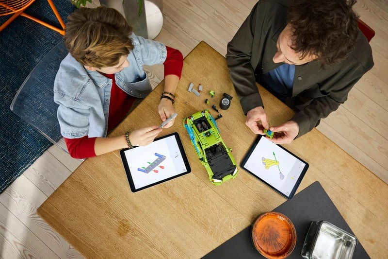 Two children building LEGO Technic Mitsubishi Eclipse car at a table with tablets and pieces visible