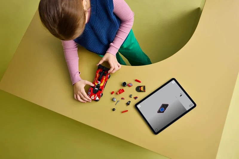 Child building a LEGO Ferrari 499P set at a table with loose pieces and tablet instructions