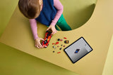 Child building a LEGO Ferrari 499P set at a table with loose pieces and tablet instructions