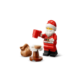 LEGO Santa minifigure holding a red mug beside a small table and brown sack