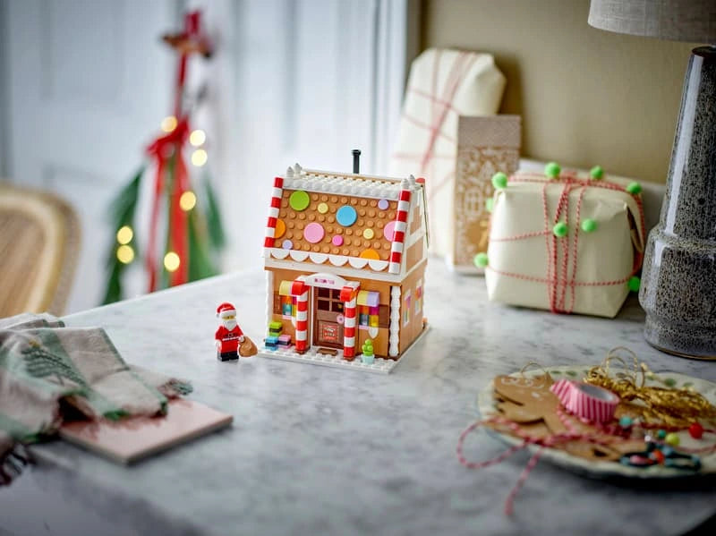 LEGO Festive Gingerbread House 40809 displayed on a table with Santa minifigure and wrapped gifts in the background
