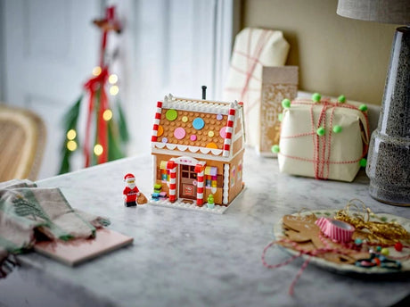LEGO Festive Gingerbread House 40809 displayed on a table with Santa minifigure and wrapped gifts in the background