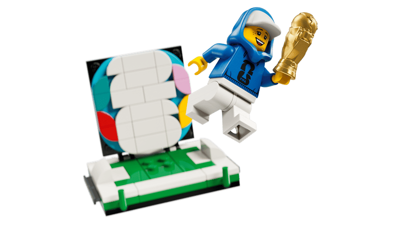 FIFA World Cup 2026 branded minifigure holding a mini gold trophy beside the removable display scene with multicolour 26 backdrop
