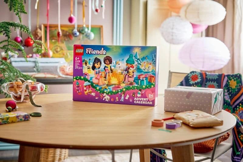 LEGO Friends Advent Calendar 2026 box displayed on a Christmas table beside wrapped presents and decorations