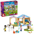 Retail box for LEGO Friends Animal Vet Clinic shown beside the assembled clinic building with minidolls, horse and small animal figures on a white background
