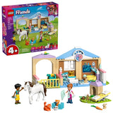 Retail box for LEGO Friends Animal Vet Clinic shown beside the assembled clinic building with minidolls, horse and small animal figures on a white background
