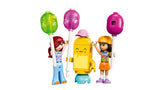 Liann minidoll with red hair and blue outfit and Paisley minidoll with dark hair and orange skirt beside a yellow ice pop mascot holding balloons