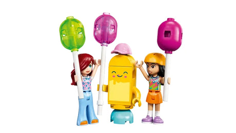 Liann minidoll with red hair and blue outfit and Paisley minidoll with dark hair and orange skirt beside a yellow ice pop mascot holding balloons