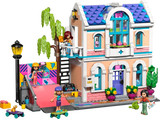 LEGO Friends Liann's Family House 42687 showing the two storey house with purple tiled roof, balcony, colourful skate ramp, tree, minidolls and outdoor accessories.