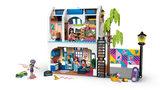 Rear view of LEGO Friends Liann's Family House 42687 showing the open two storey interior, furnished rooms, minidolls, outdoor skate area, climbing ladder and colourful wall mural.