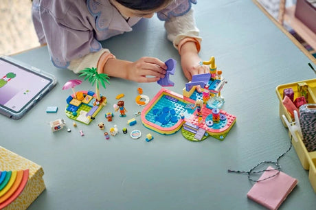 Child building LEGO Friends Fun Water Park Day with pieces and instructions on the floor