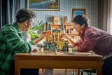 Two people building a LEGO Hogwarts castle set at a table with the castle model and loose pieces