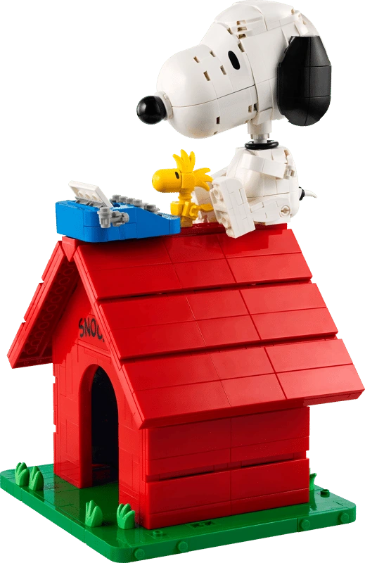 Brick built LEGO Snoopy seated on the red doghouse roof beside Woodstock and a blue typewriter, with the model on a green base.
