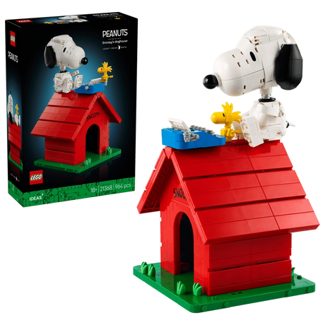 LEGO Ideas Peanuts Snoopy's Doghouse 21368 retail box beside the completed red doghouse, with Snoopy, Woodstock and a blue typewriter on the roof.