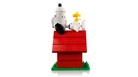 Side view of LEGO Snoopy lying on the red doghouse roof with Woodstock sitting on his belly, above the green base.