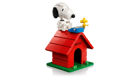 Completed brick built LEGO Snoopy's Doghouse with Snoopy seated on the roof beside yellow Woodstock and a blue typewriter.