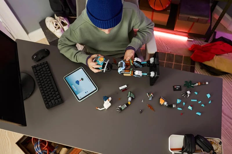 Child building a LEGO Fortnite KIT set at a table with pieces and tablet instructions
