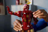 Person adjusting both arms of the LEGO Iron Man Mark 3 model, shown from the rear with one hand raised