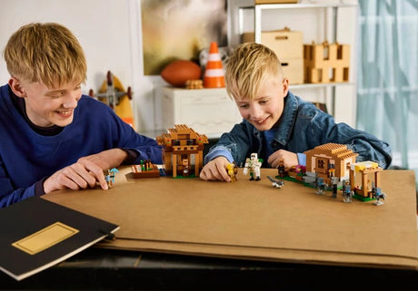 Two children playing with a LEGO Minecraft village set on a table