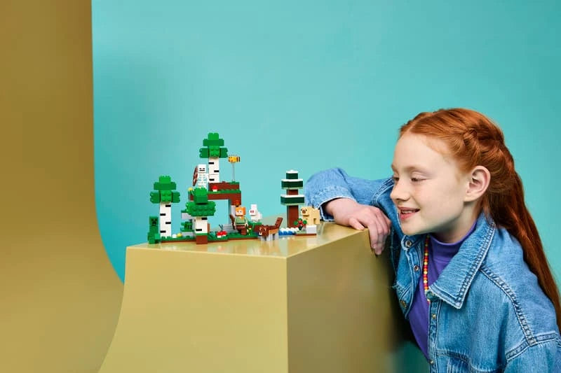 Child looking at a LEGO Minecraft shelter build displayed on a table