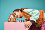 Child playing with LEGO Friends Nature Glamping Cabin on a table with mini-dolls and accessories visible