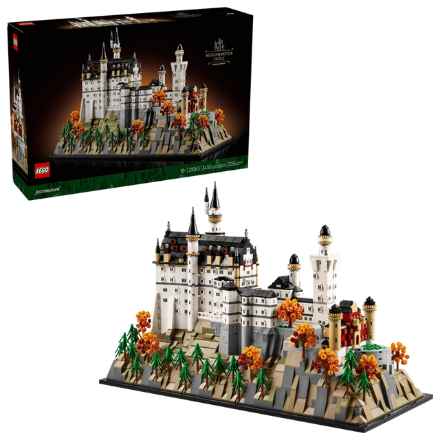 LEGO Neuschwanstein Castle 21063 box shown above the completed castle model with landscaped base, pine trees and orange autumn trees on a black background