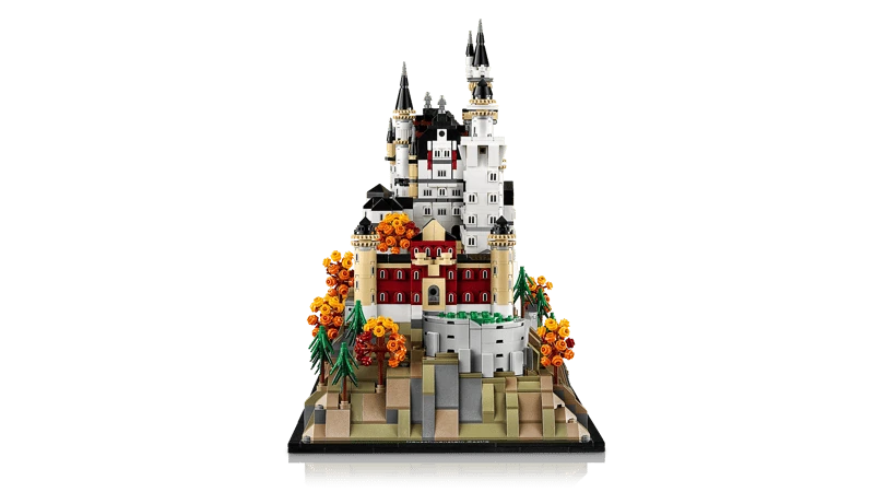 LEGO Neuschwanstein Castle 21063 end view showing the castle rising behind the front buildings, rocky base, pine trees and orange autumn trees