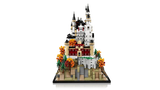 LEGO Neuschwanstein Castle 21063 end view showing the castle rising behind the front buildings, rocky base, pine trees and orange autumn trees